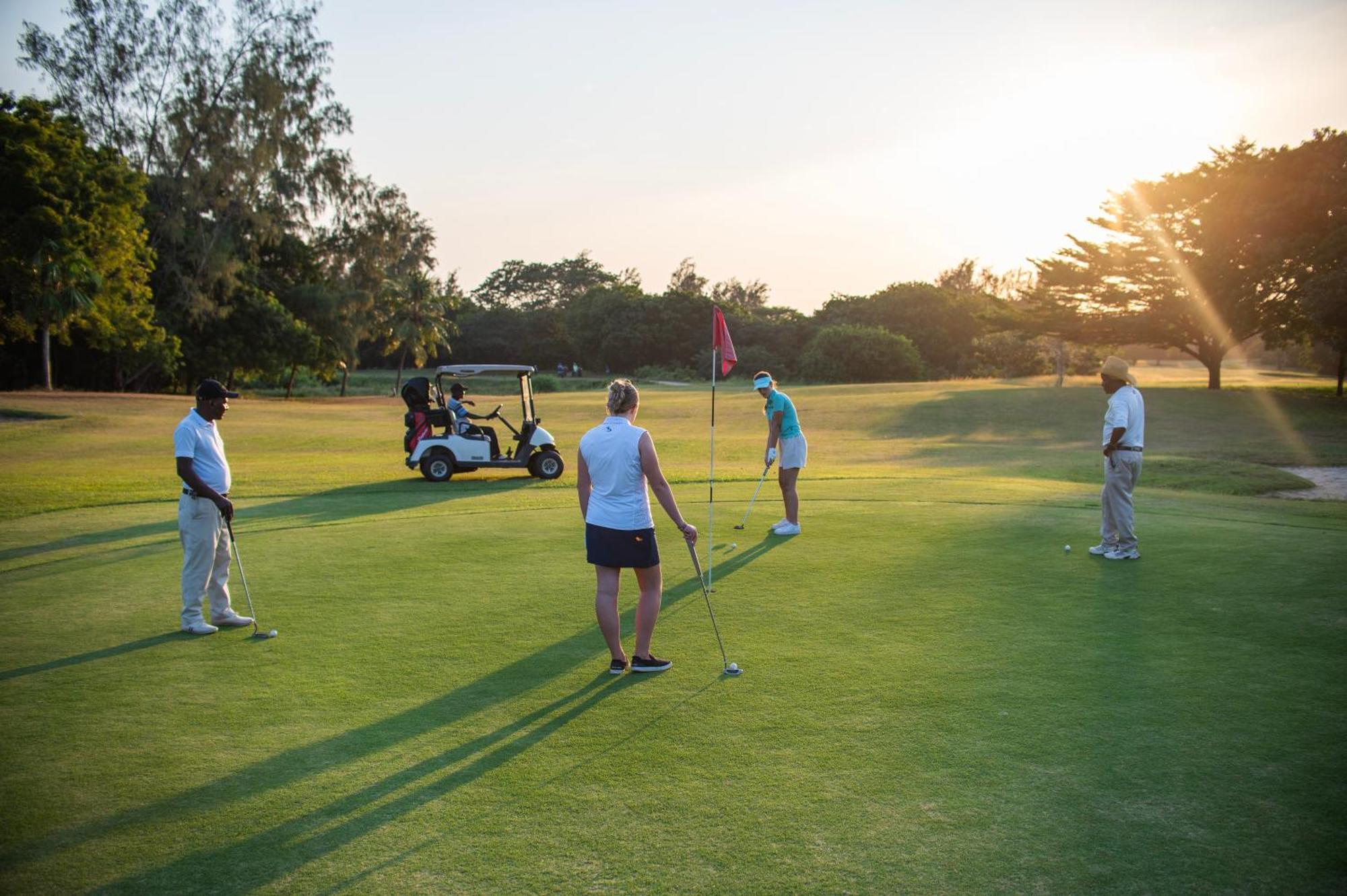 Diamonds Leisure Beach & Golf Resort Диани Бийч Екстериор снимка Golfers putting on the 18th green at the Royal Pines Resort